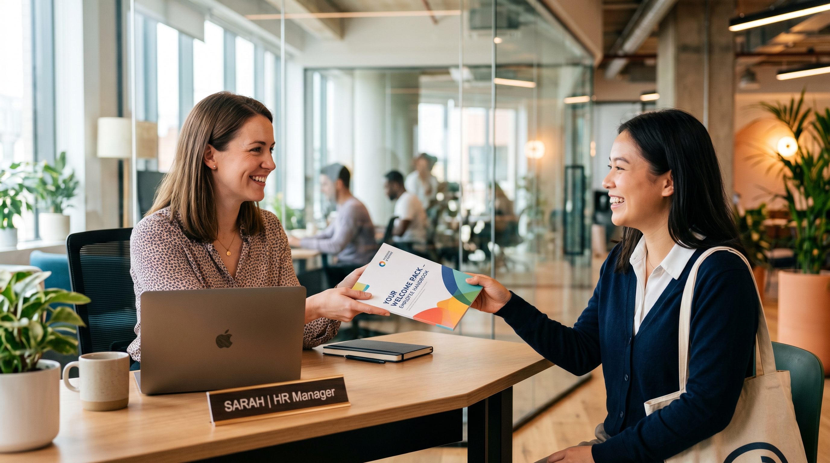 New hire holding her employee handbook and smiling at the camera in a modern office