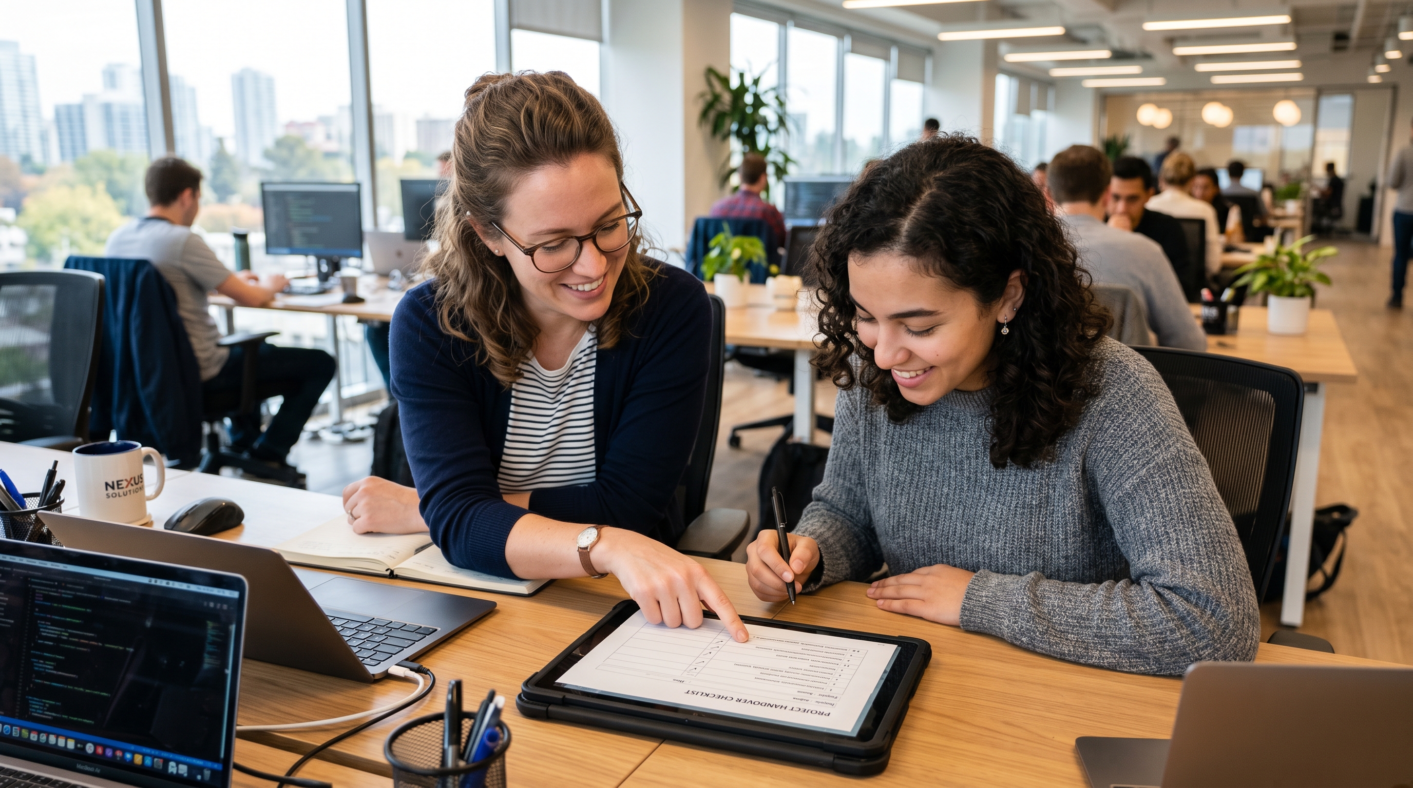 Two colleagues reviewing a work handover checklist before a coworker starts maternity leave