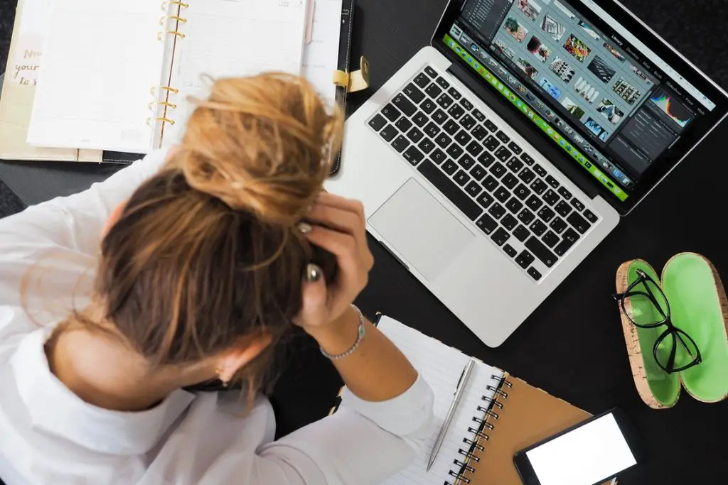 Women sitting in front of a laptop with her hands on her head. Work from home