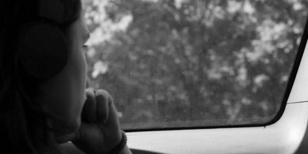 Grayscale photo of a woman inside a car practicing intrapersonal communication.