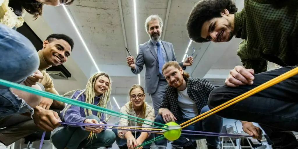 below view of a happy creative team having fun while playing a game with a tennis ball together 