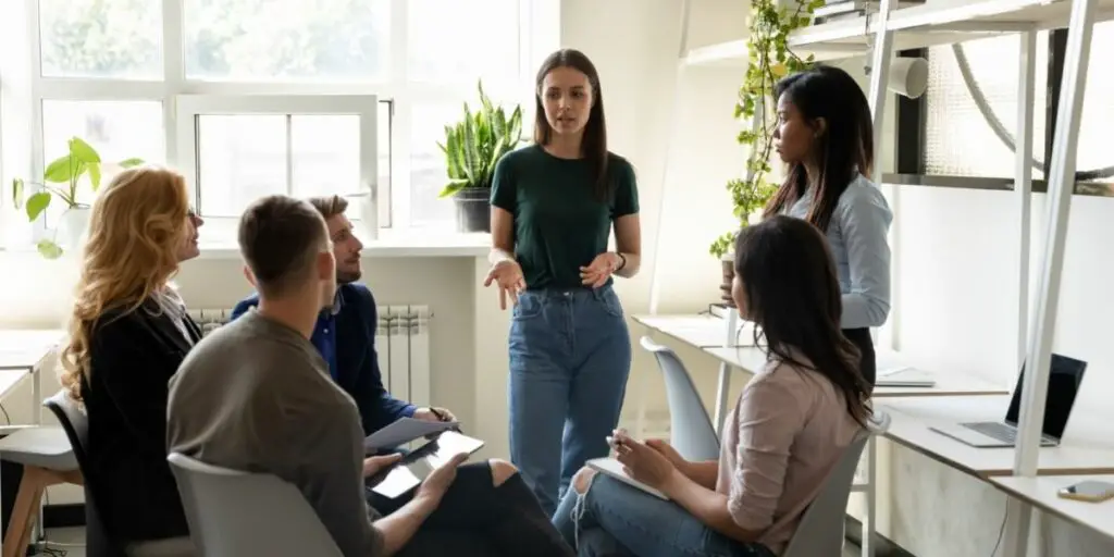 Diverse office workers listen to team leader at a group meeting