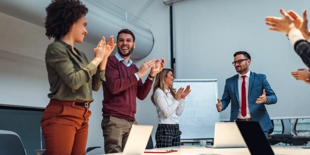 15 Examples of Interpersonal Skills That Will Help You Grow 2 shot of a group of coworkers applauding after a successful presentation in a boardroom