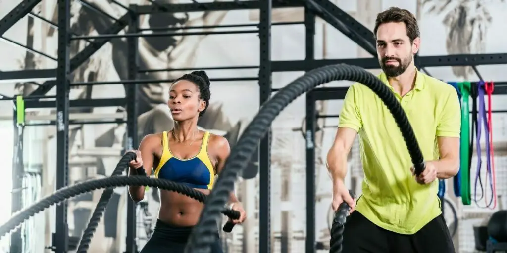 An athletic young couple with battle rope doing exercise in functional training