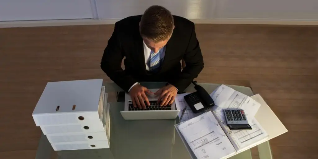 businessman under pressure working overtime late into the evening sitting at his desk