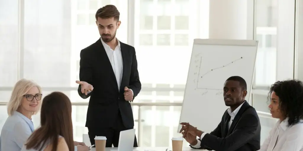 Confident coach communicating with international company staff pointing on caucasian worker