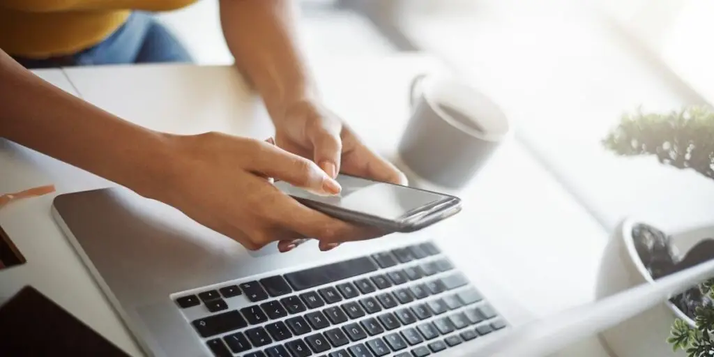 Close shot of an unrecognizable female designer using a cellphone in her home office