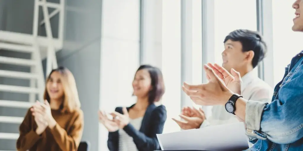 Young business people clapping hands during meeting in office. incentive theories. 