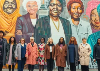 a diverse group of women pioneers standing proudly together in front of a mural depicting their accomplishments.